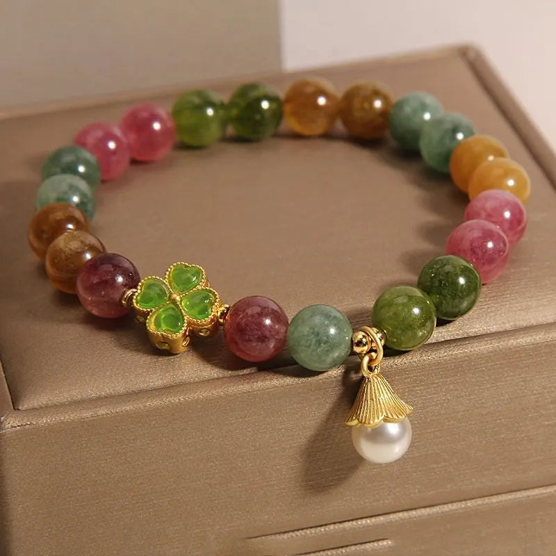 Colourful mixed-material women's bracelet with a four-leaf clover charm and a pearl pendant on a geometric chain.