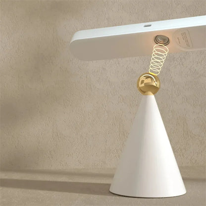 White geometric desk lamp with magnetic base and touch control on a wooden table.