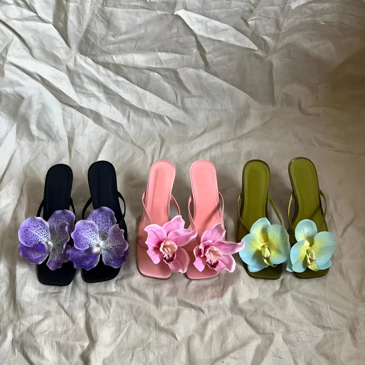 Pink women's sandals with a satin upper, artificial white Phalaenopsis flower, square toe, and a mid-height heel.