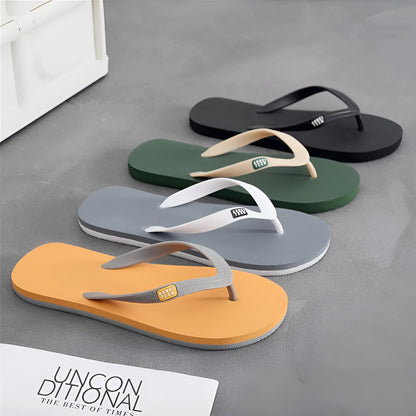 Men's black flip-flop slippers with EVA upper and textured rubber sole on a sandy background.