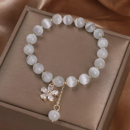 Women's white cat's eye crystal bracelet with flower tassels and a morganite safety buckle pendant.