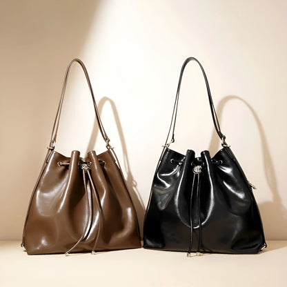 Brown genuine leather retro-style bucket bag with a single shoulder strap showing internal zipped compartments.