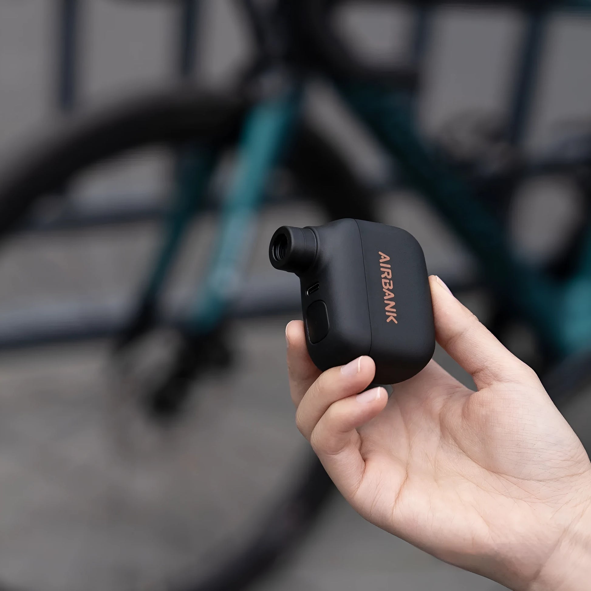 Black AS100 electric bicycle pump with digital display, USB charging port, and included waterproof bag
