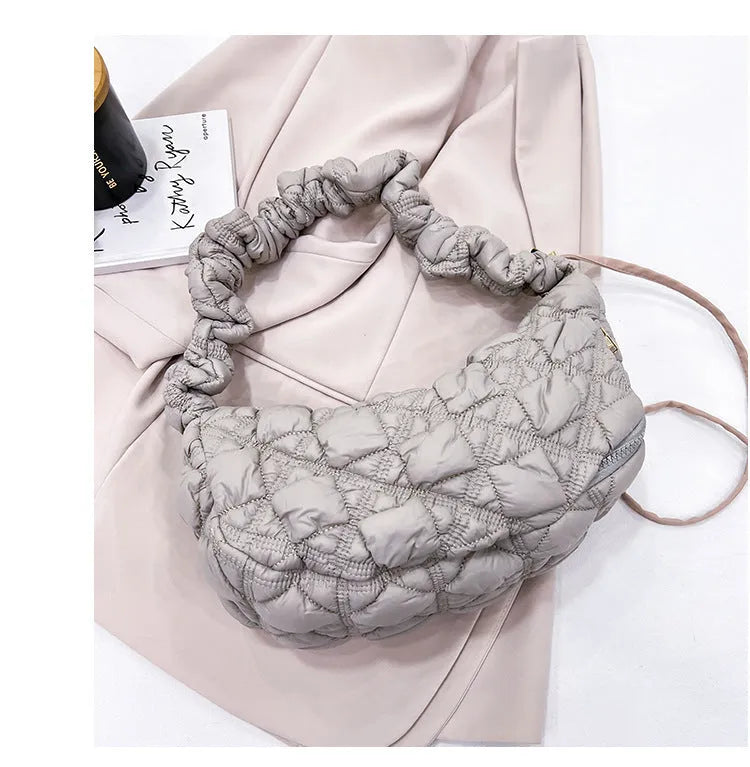 Women's light grey nylon underarm messenger bag with adjustable long strap, shown worn crossbody.