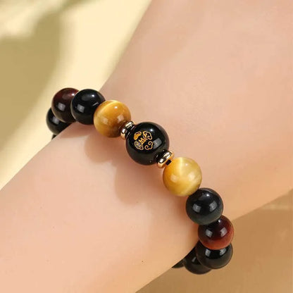 Handcrafted black agate and tiger eye stone beaded bracelet with a central carved zodiac deity charm.