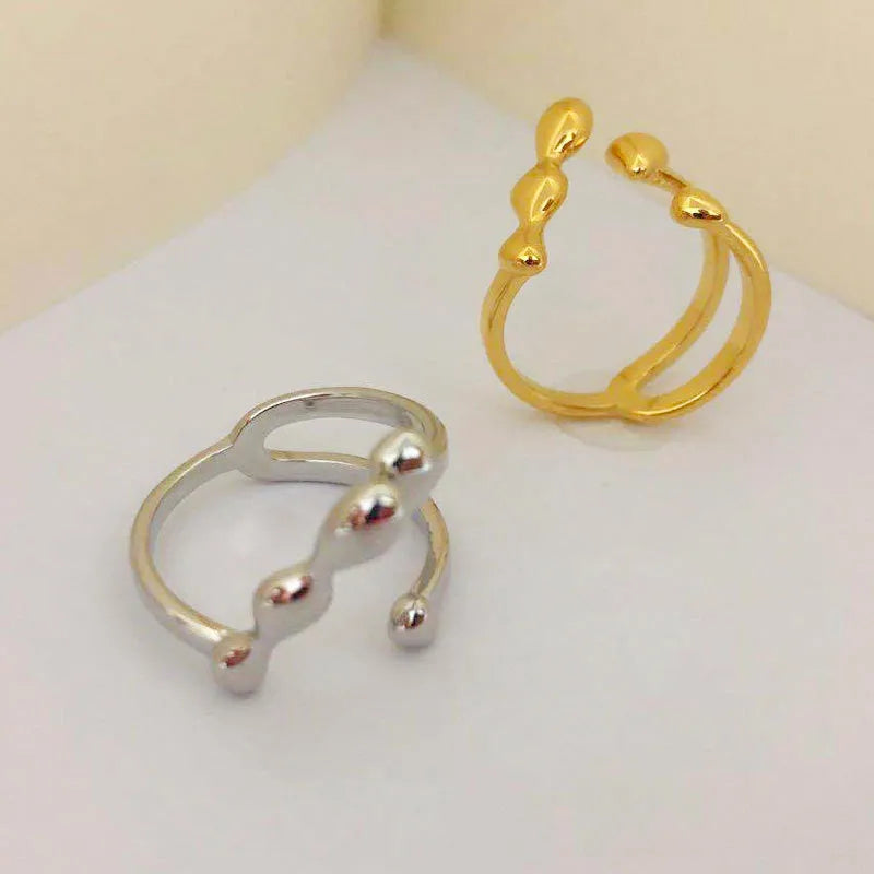 Gold adjustable open ring with spherical details on a woman's hand, showing the 1cm gap.