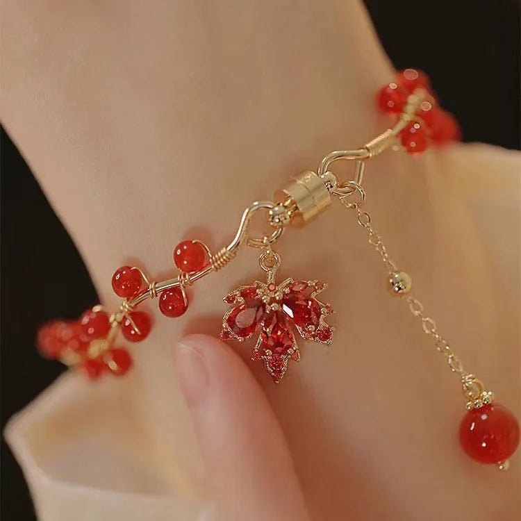 Red ginkgo leaf charm magnetic bracelet for girls on a wrist, showing maple leaf design details.