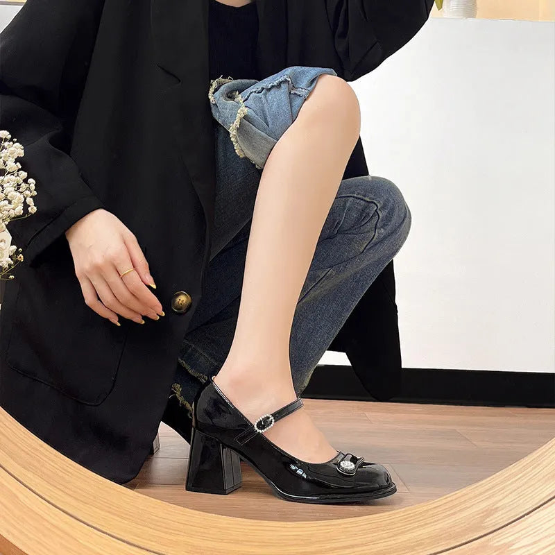 Black patent leather women's high heels with a chunky heel, round toe, and buckle fastening.