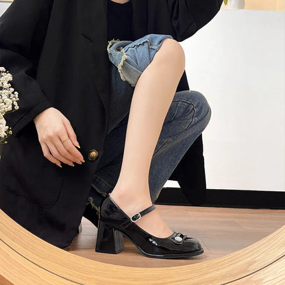 Black patent leather women's high heels with a chunky heel, round toe, and buckle fastening.