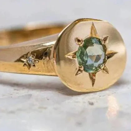 Golden ring with oval asterism zircon, star shape, and adjustable opening on a plain background