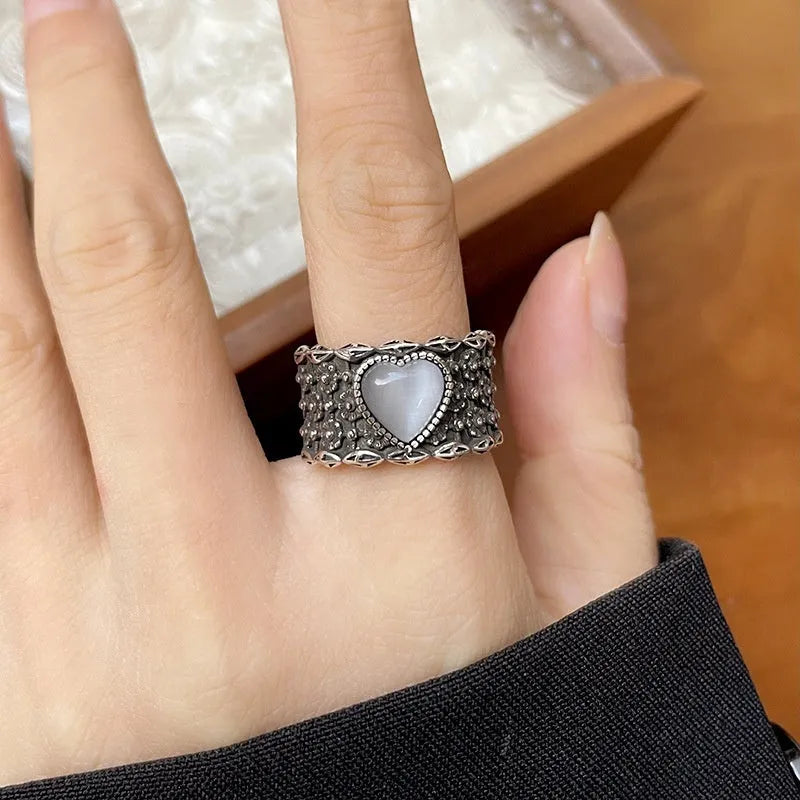 Retro style wide silver heart shape ring with adjustable band on a wooden surface