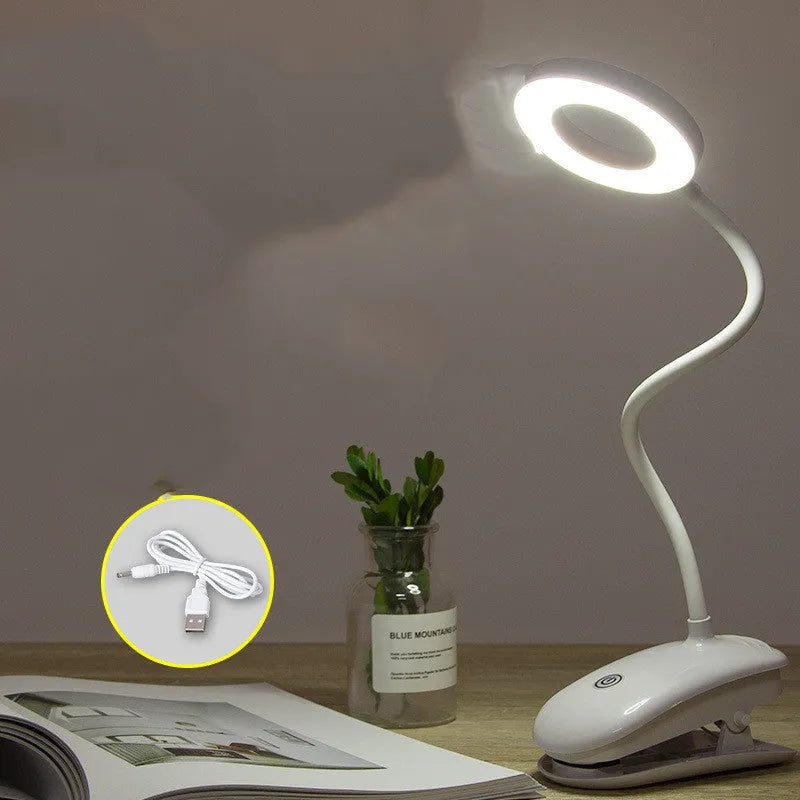 A modern white clip-on rechargeable desk lamp with a touch-sensitive switch and a plastic shade.