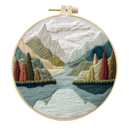 Complete DIY embroidery kit with 15cm bamboo frame, pre-printed landscape fabric, threads, and needles laid out.