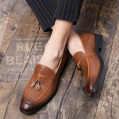Men's black pointed toe slip on shoes with a tassel detail on the upper.