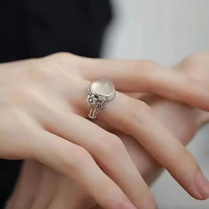 Adjustable open-mouth copper vintage ring with U-shape and antiqued white chalcedony-style finish on a wooden surface.