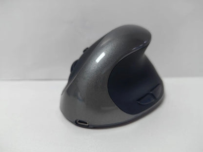 Ergonomic vertical mouse in black, shown next to a laptop, highlighting its unique upright shape and USB receiver.