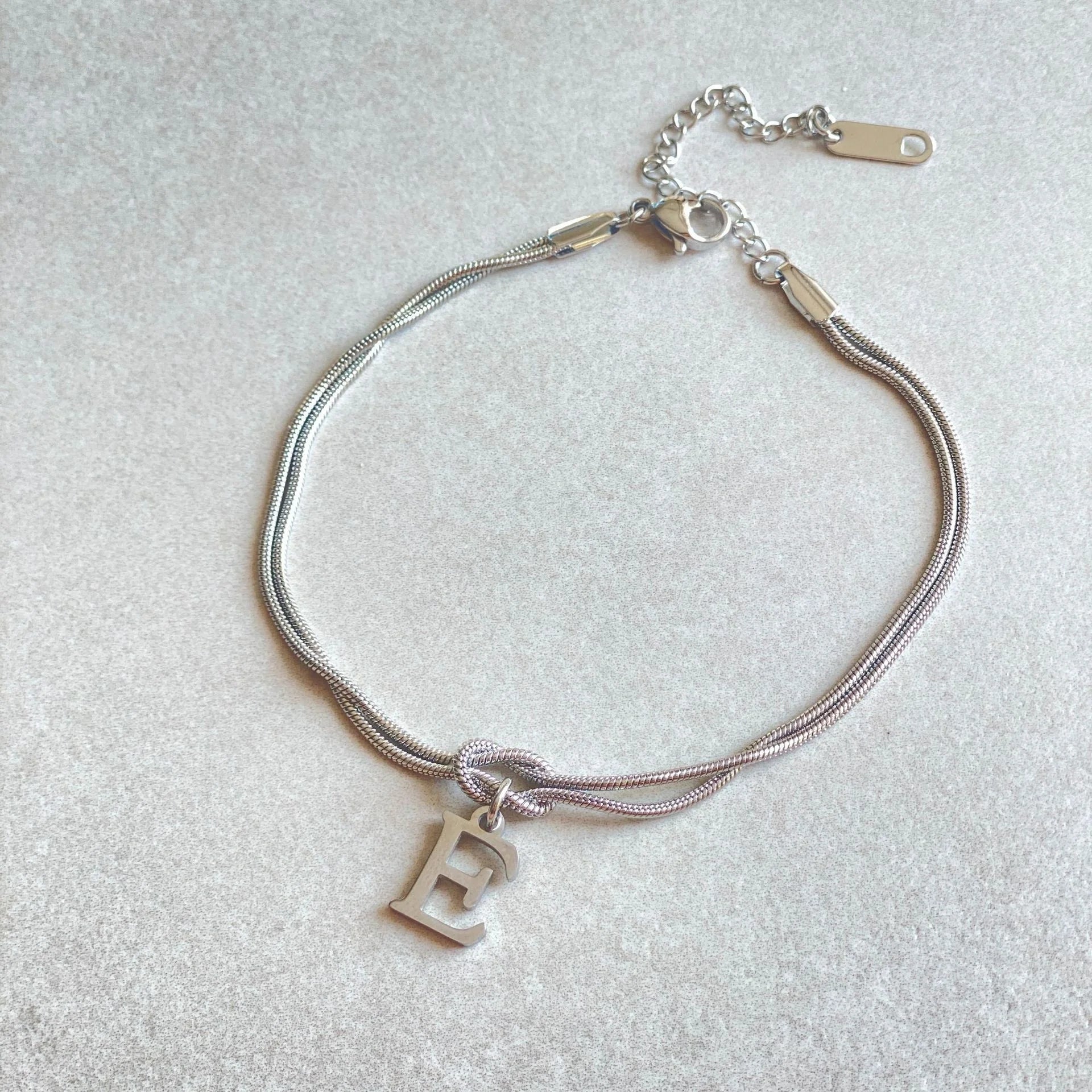 Elegant letter charm bracelets for women in gold and silver tones, featuring a delicate snake chain design and personalised letter charms.