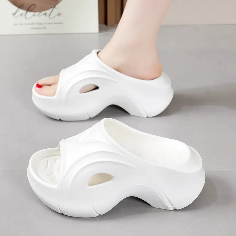 Women's white thick-soled EVA slippers with a round toe on a beach background.