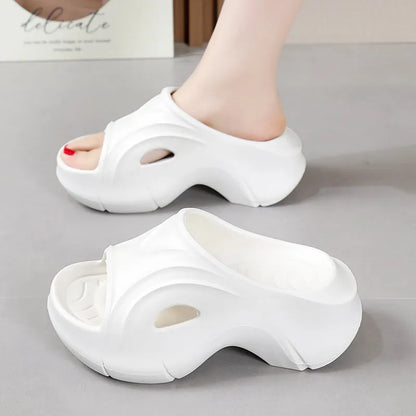 Women's white thick-soled EVA slippers with a round toe on a beach background.