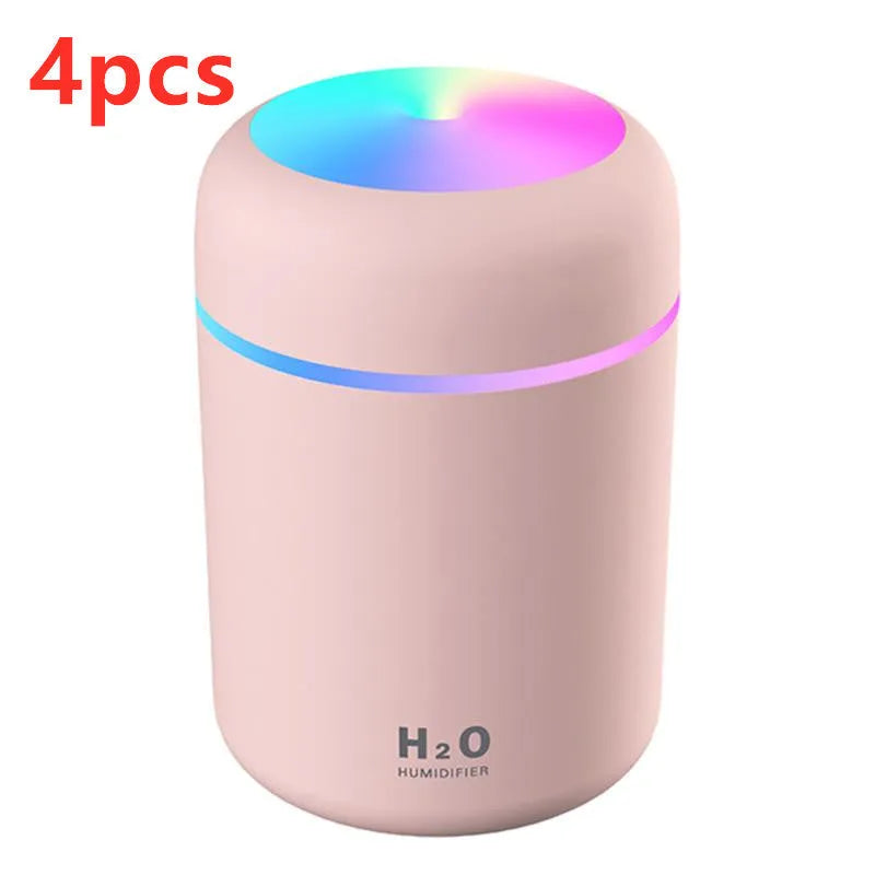 Pink USB desktop humidifier with LED lights and water tank on wooden desk