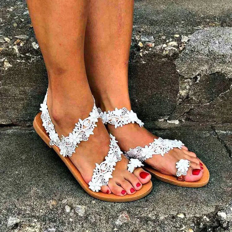 White casual flat sandals with rhinestone and floral decoration on a glossy PU upper.
