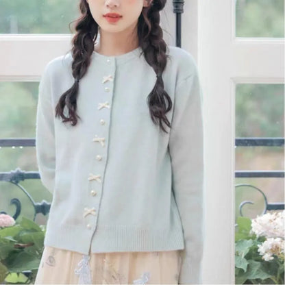 Women's acrylic cardigan sweater with pearl button bow detail in light yellow colour