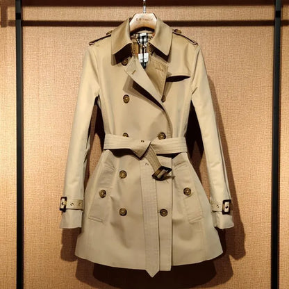Khaki women's double-breasted trench coat with flight sleeves on a hanger.