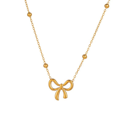 Gold adjustable bow necklace on a cross-link chain, showing the detailed pendant and clasp.