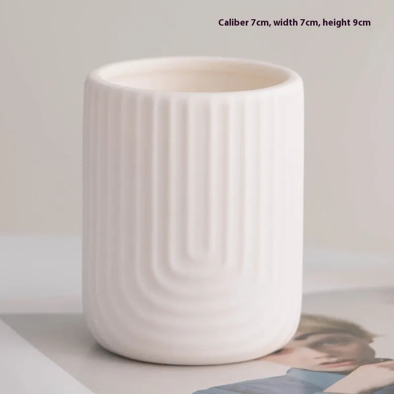 Set of ten round white ceramic candlesticks with minimalist relief patterns on a dining table