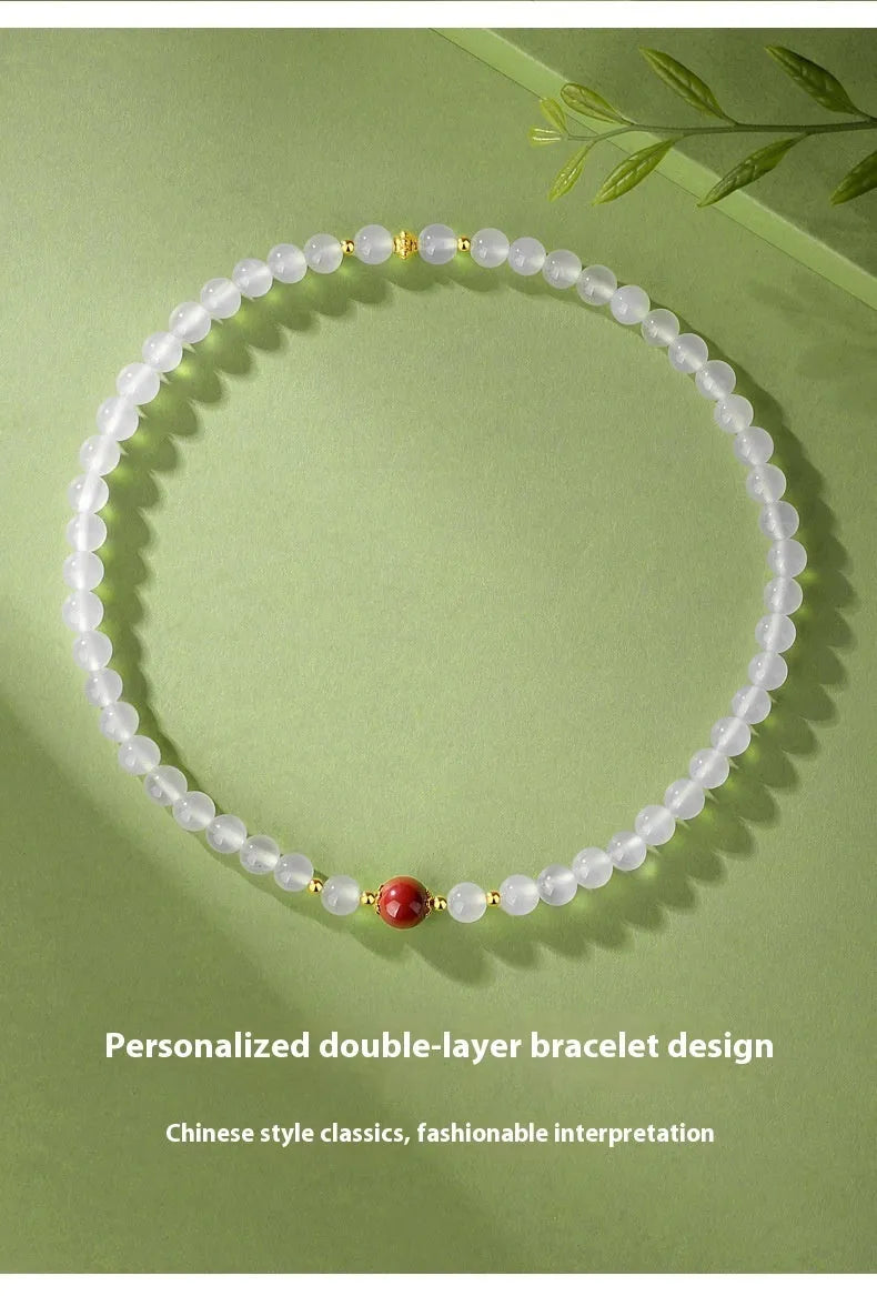 Close-up of a women's double layer bracelet with polished white agate and jequirity bean beads.