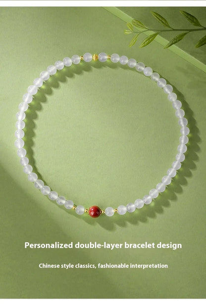 Close-up of a women's double layer bracelet with polished white agate and jequirity bean beads.