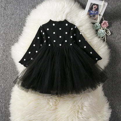Baby girl wearing a long sleeve black tutu dress with lace detail for a birthday party.