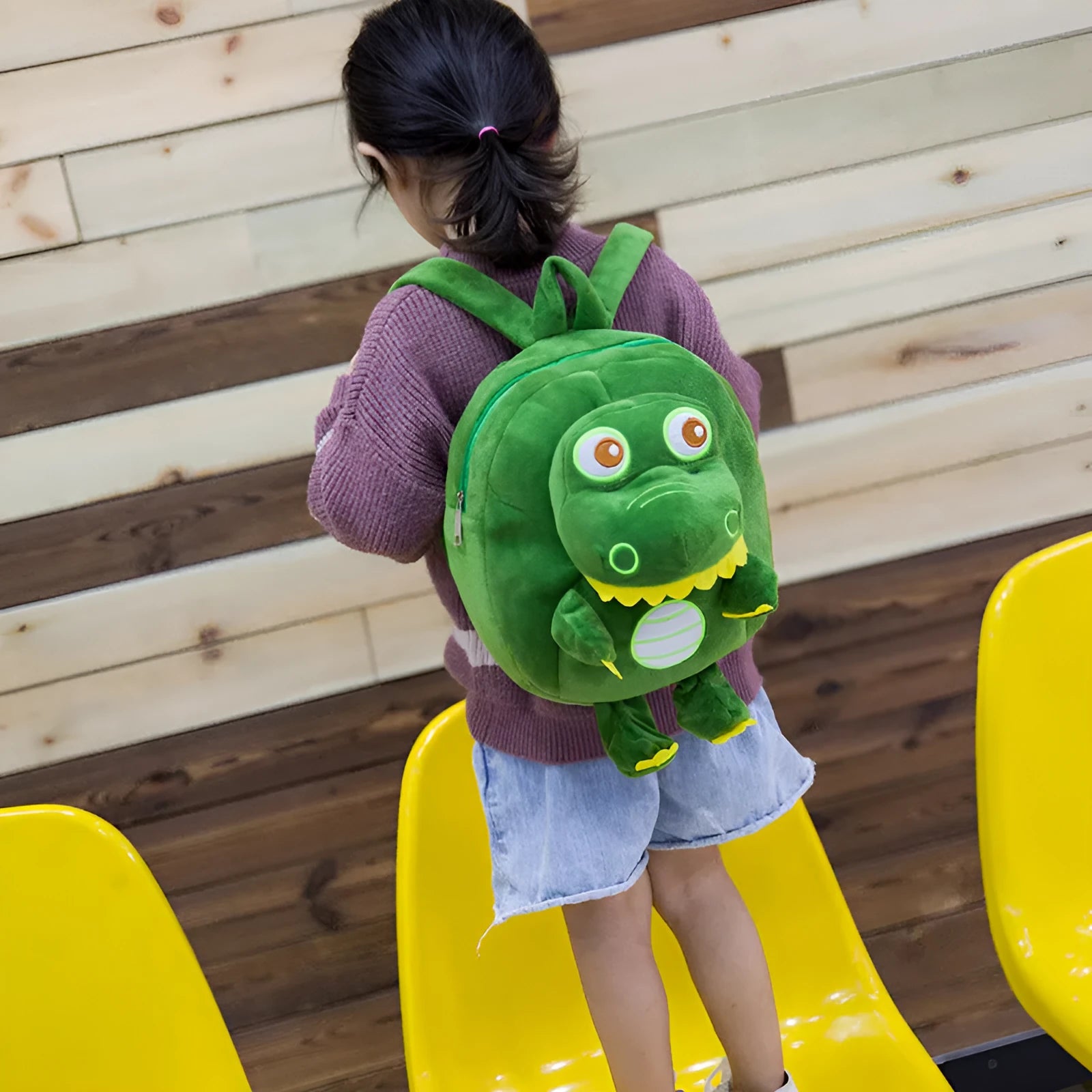 Soft blue plush children's backpack with an embroidered green dinosaur character and a soft handle.