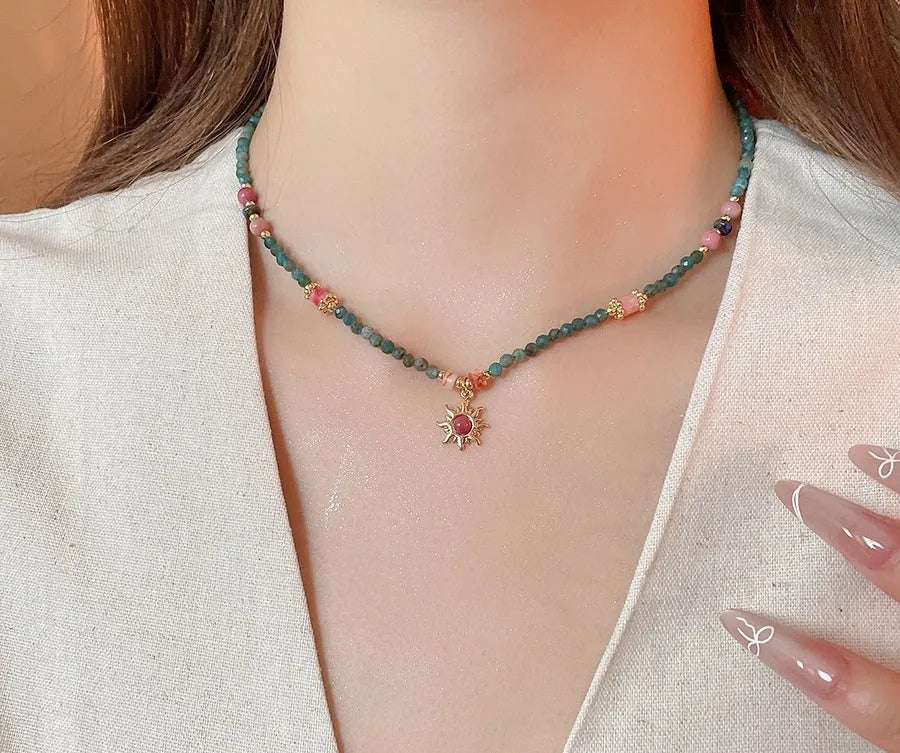 Geometric sun stone pendant on a freshwater pearl necklace with gold and blue electroplated finish.