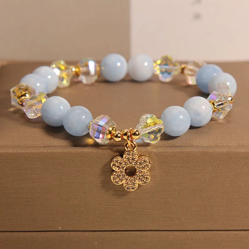 Women's aquamarine crystal bracelet with four-leaf clover charm and pearl details on wrist