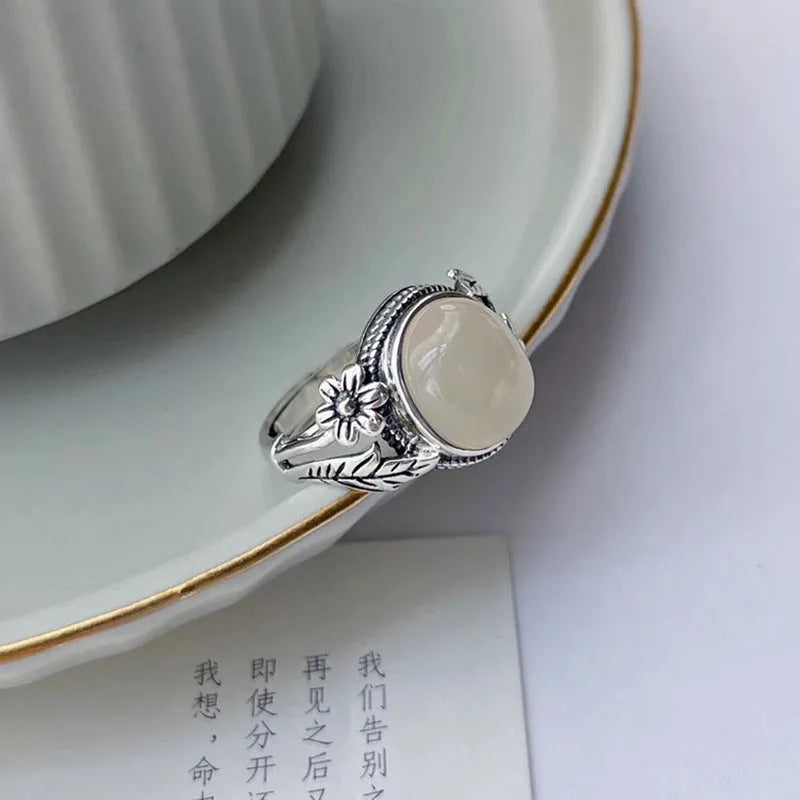 Adjustable open-mouth copper vintage ring with U-shape and antiqued white chalcedony-style finish on a wooden surface.