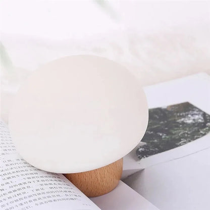 White silicone mushroom-shaped LED night light with a wooden base and touch control.
