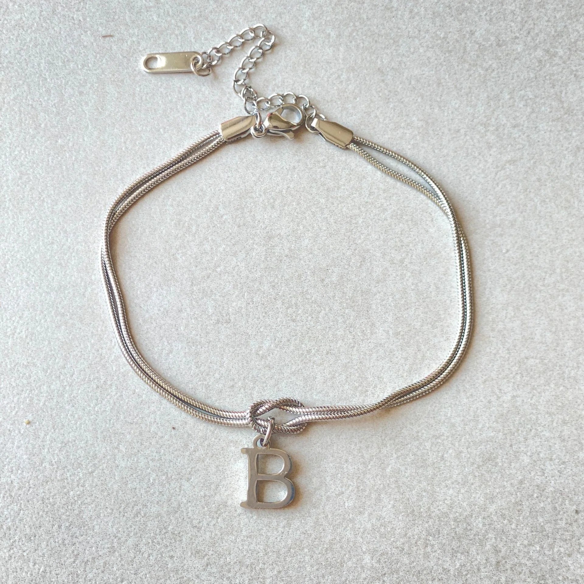 Elegant letter charm bracelets for women in gold and silver tones, featuring a delicate snake chain design and personalised letter charms.