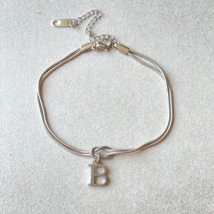 Elegant letter charm bracelets for women in gold and silver tones, featuring a delicate snake chain design and personalised letter charms.