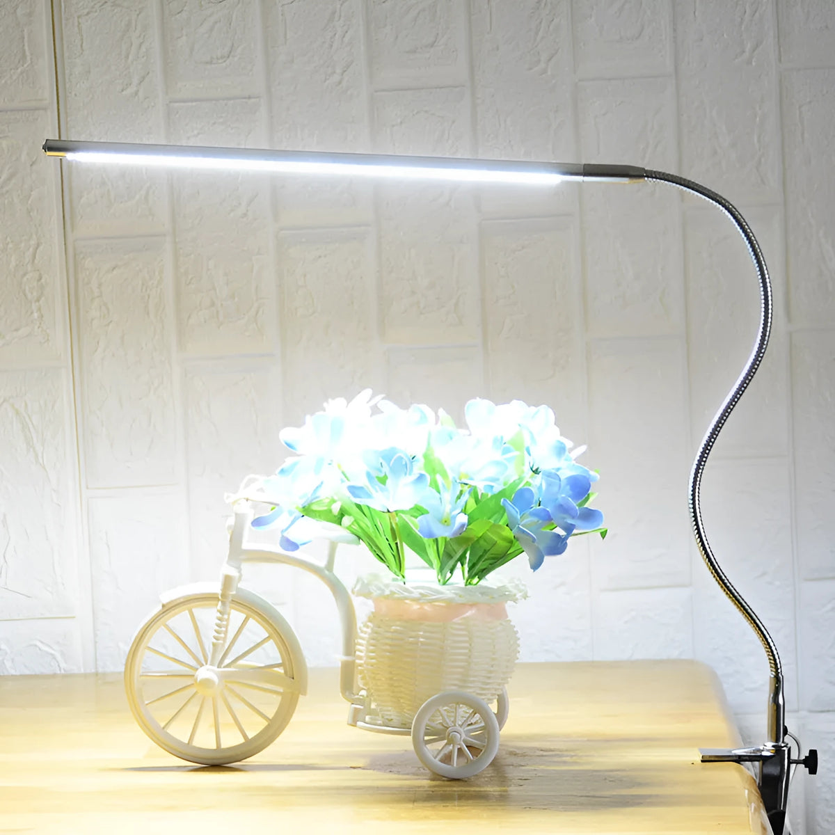 Silver aluminium alloy USB-powered LED nail table lamp with a long arm clip attached to a table edge.