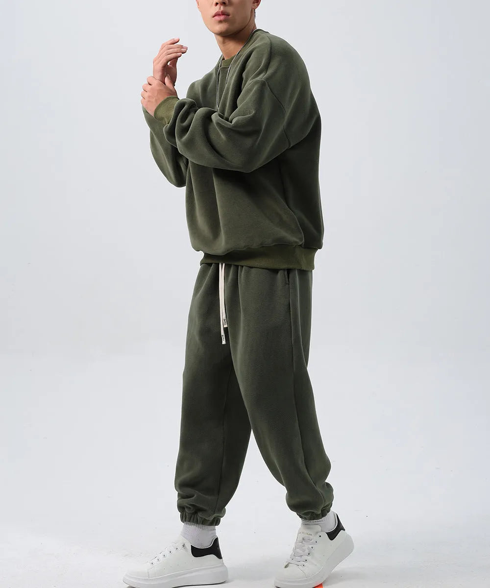 Man wearing a loose-fit army green polar fleece tracksuit with a crew neck jacket and matching padded trousers.