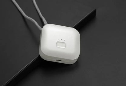 Small pink wearable air purifier pendant on a necklace, showing USB charging port and single button.