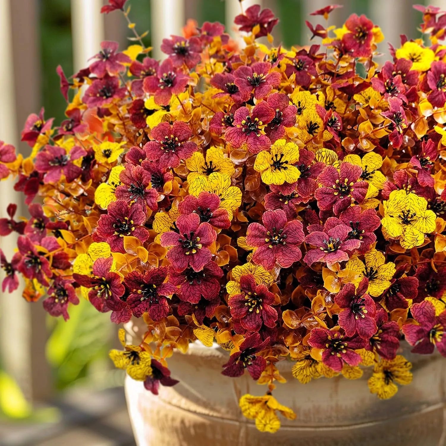 Artificial flower bouquet in autumn colours of red, yellow, and orange made from plastic and silk.