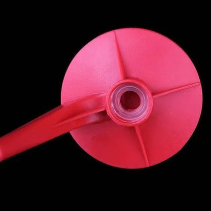 Red plastic Magic Tap soda bottle dispenser attached to an inverted 2-litre bottle on a kitchen table.