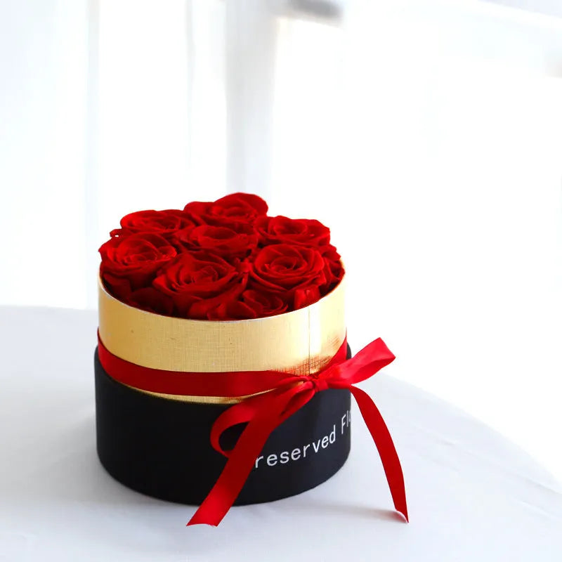Luxury gift box containing an arrangement of preserved red eternal roses on a dark background.