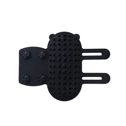 Silicone cat grooming comb with adjustable strap mounted on a table leg, shown in green.