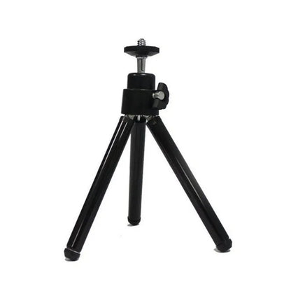 Black mini camera tripod with extended legs and a separate U-shaped universal phone clip on a table.