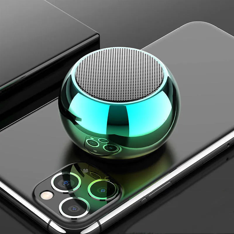 Small round aluminium Bluetooth speaker in gradient blue, showing compact size next to a USB cable.