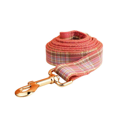 Red plaid cloth dog collar and leash set with matching bow on a white background