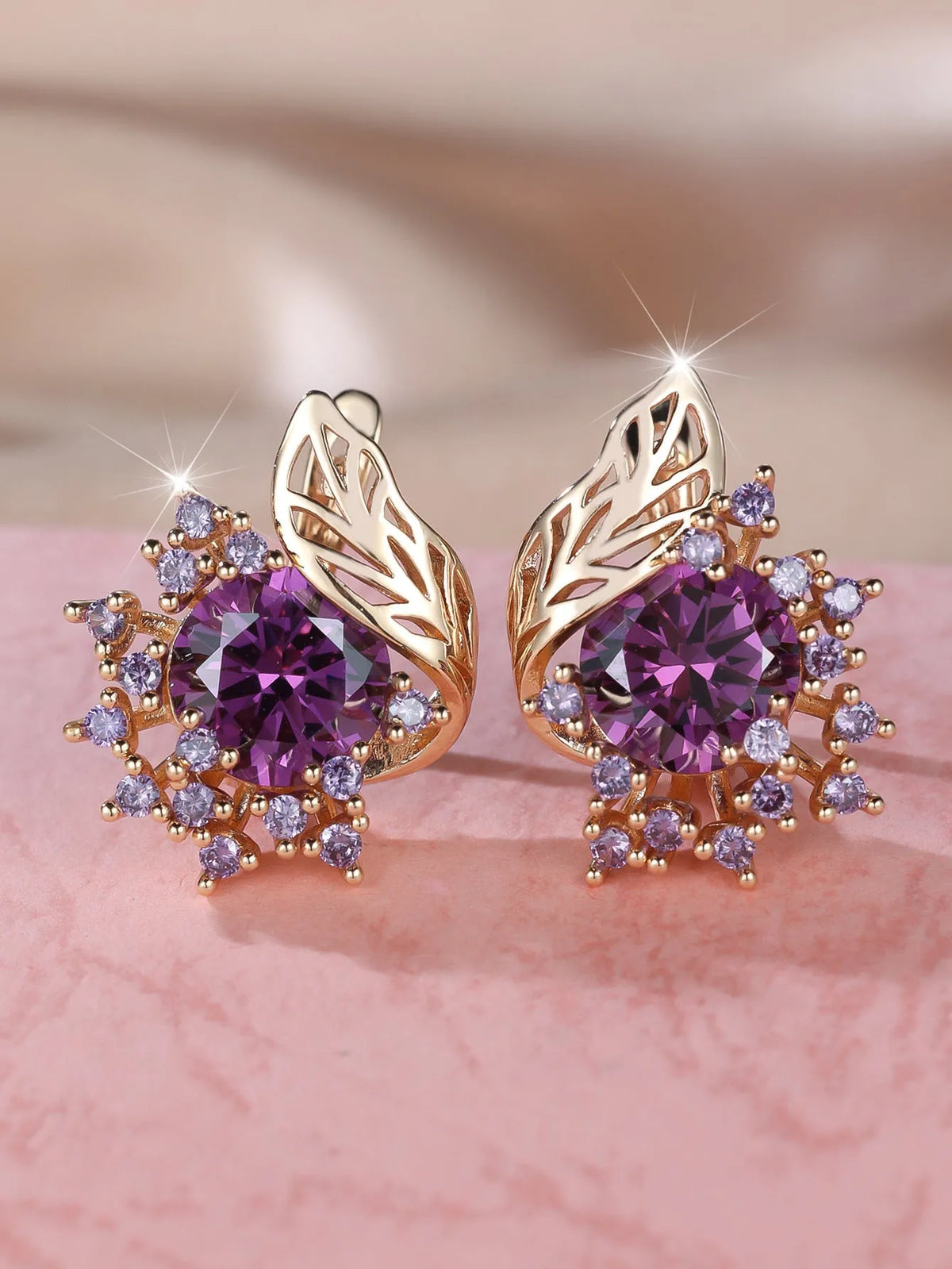 Rose gold plated women's stud earrings with a round flower shape, feather detail, and a central cubic zirconia stone.